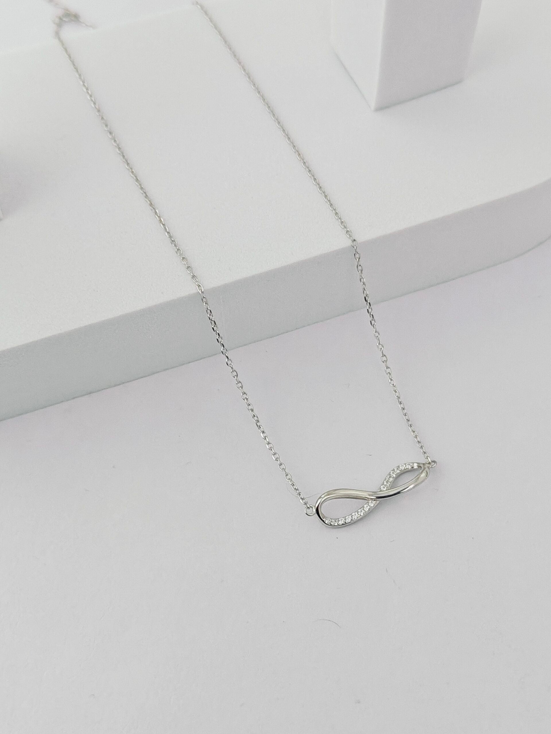 Silver infinity necklace on a light gray background